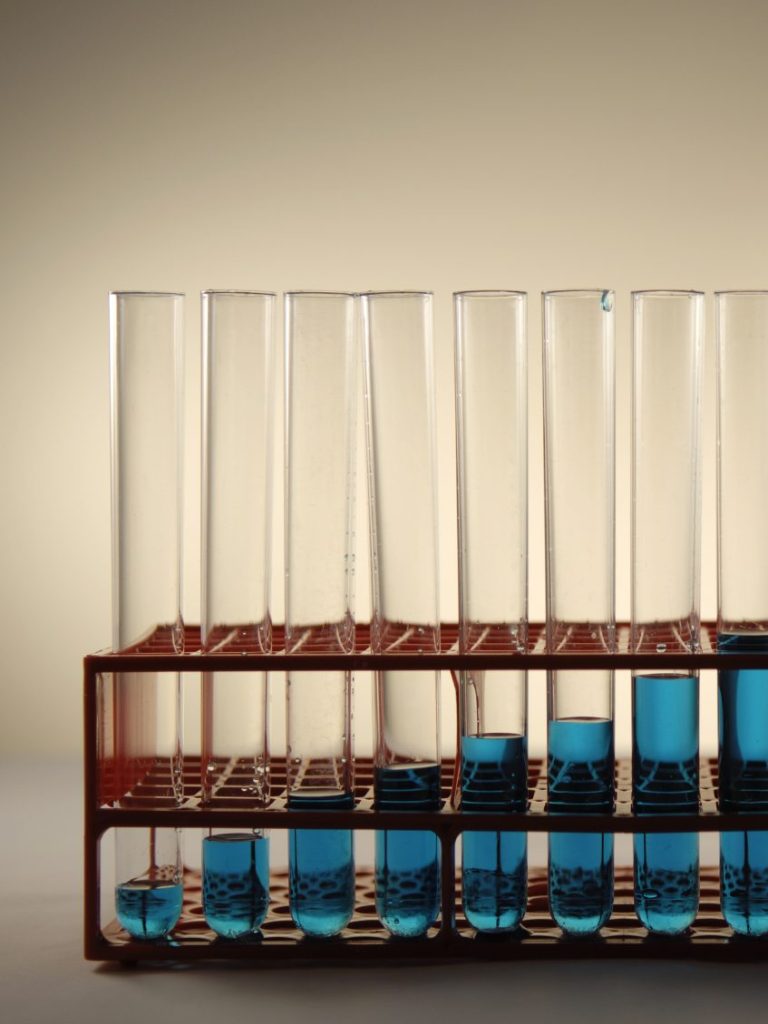 A row of test tubes in a rack with increasingly more liquid in them from left to right.